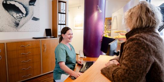 Zahnarzthelferin am Emfnag mit Patientin